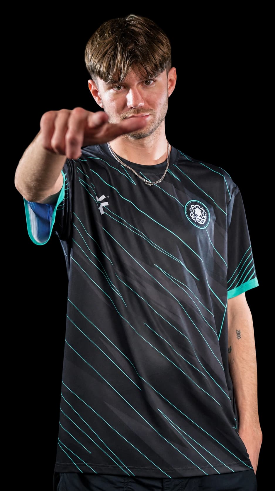 Player in a black and teal esports jersey pointing at the camera